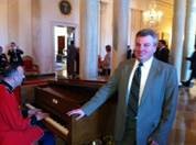 Mark Standing with a suit next to a man playing piano