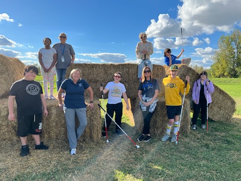 Cindy and other staff pose with 7 middle school students in front of hay bales this fall at a pumpkin patch.