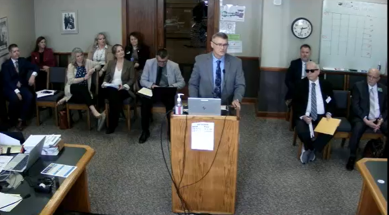 Paul stands behind a podium testifying in a room about NDVS/SB's budget to the Senate Appropriations Committee in March 2025.