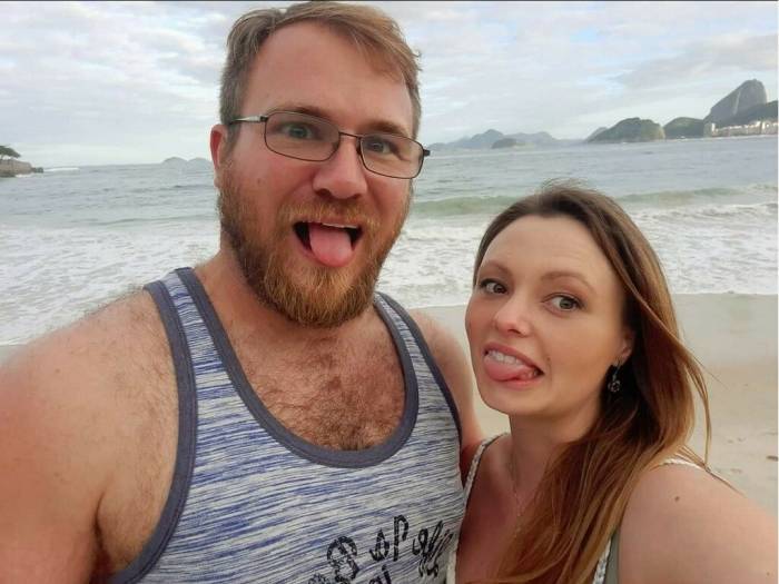 BreAnna and her husband acting silly on the beach, sticking out their tongues at the camera.