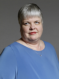professional image of Neva Fairchild, a woman of middle age with gray hair, wearing a blue shirt