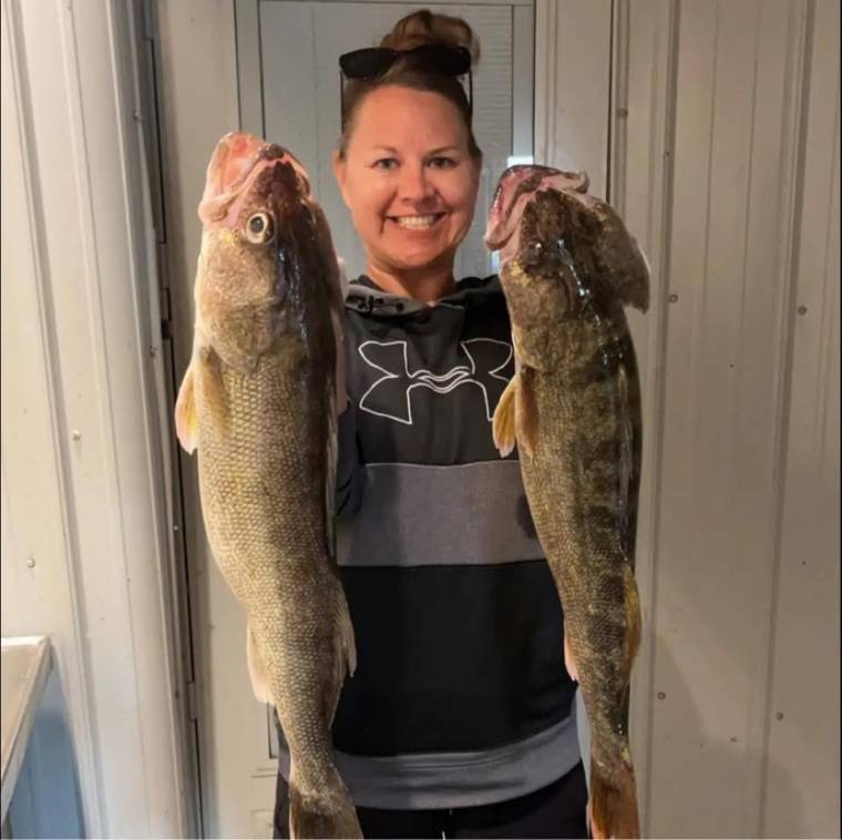 Tallena smiles as she holds two large fish that she caught.